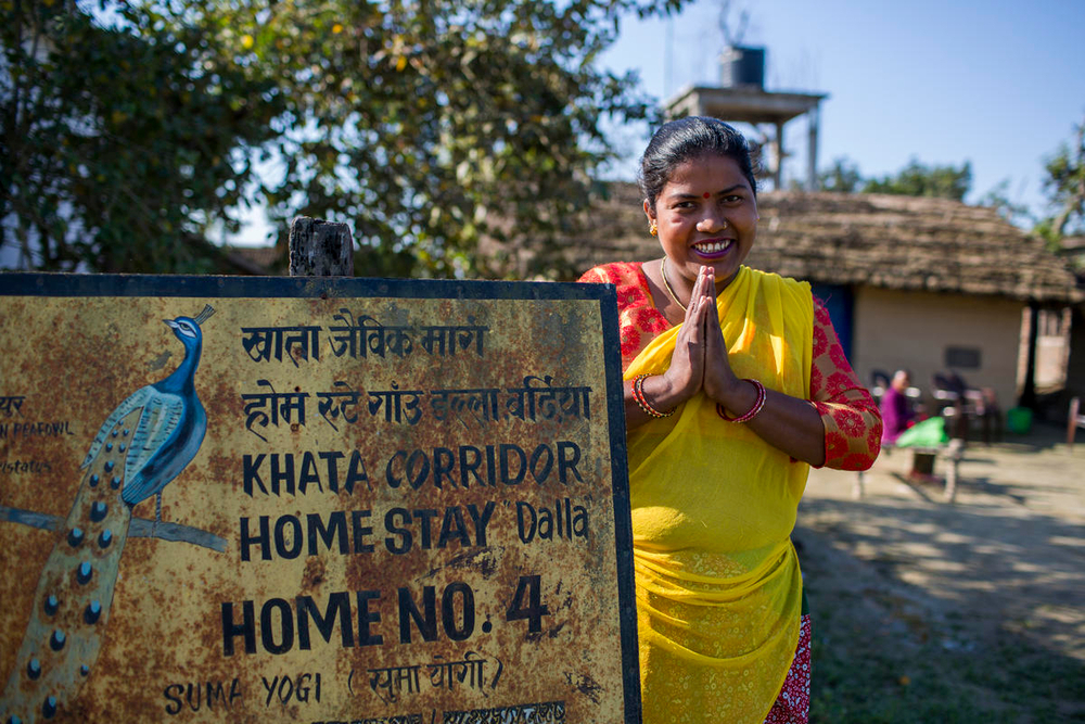 vrouw stat voor bord met pauw en homestay erop