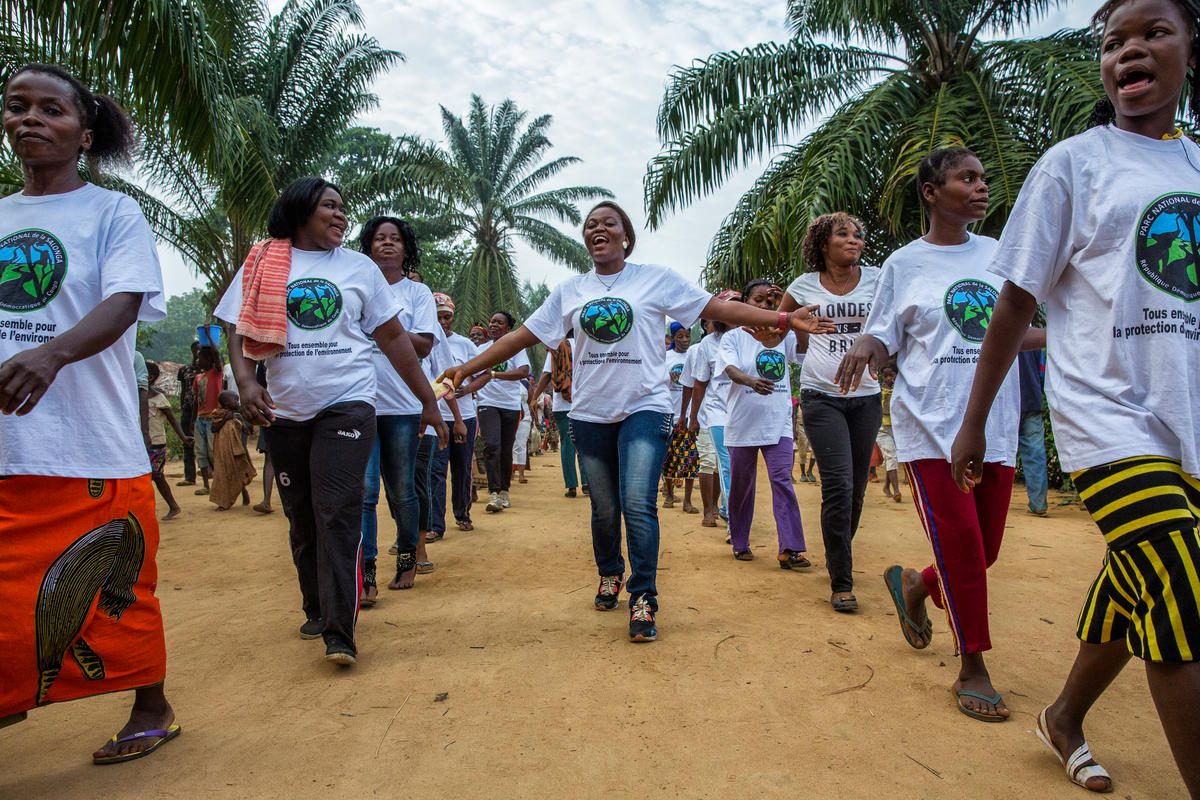 vrouwen lopen tussen palmbomen over onverharde weg