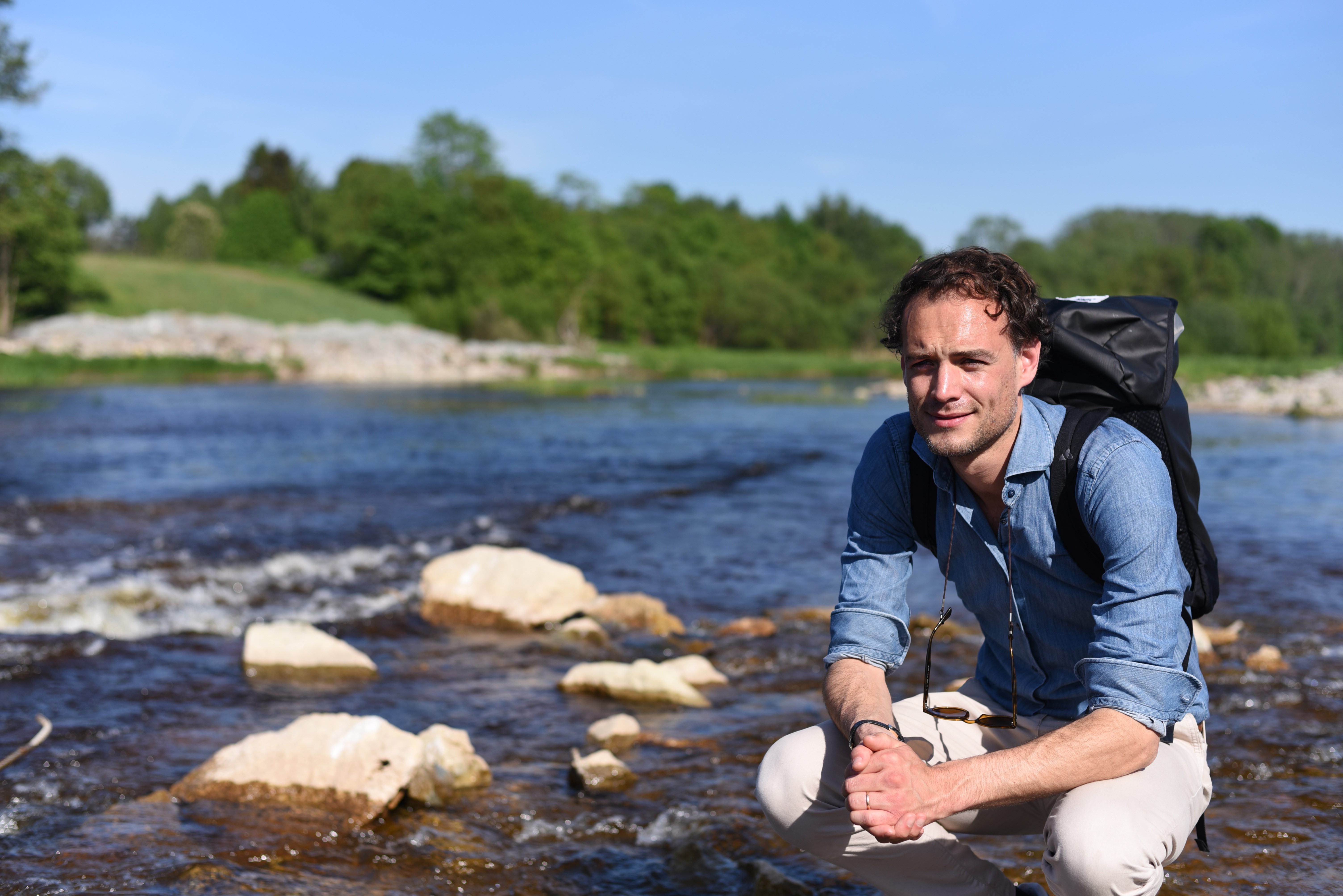 Oskar gehurkt naast rivier