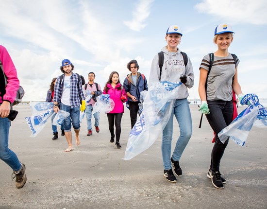 mensen lopen op strand met vuilniszakken