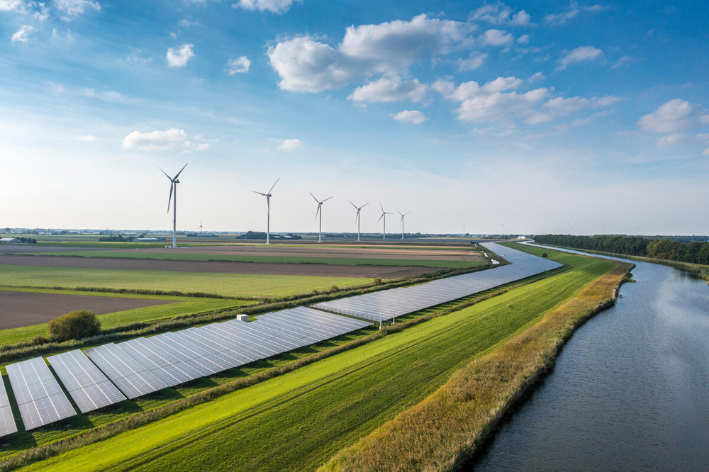dijk met zonnepanelen en windmolens in weilanden met tulpen