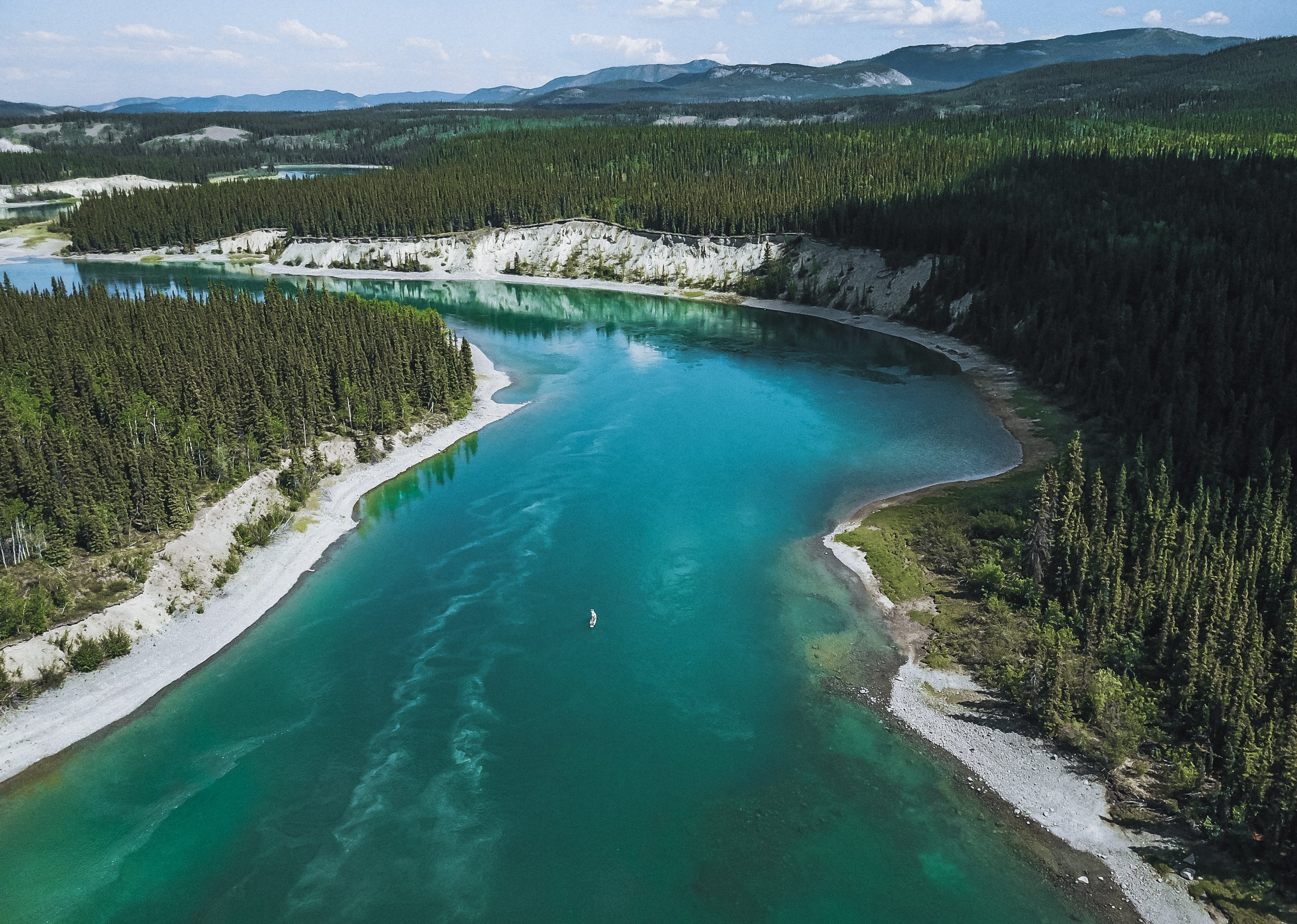 Yukon rivier in Canada, van bovenaf, blauw water met dennen langs de kant
