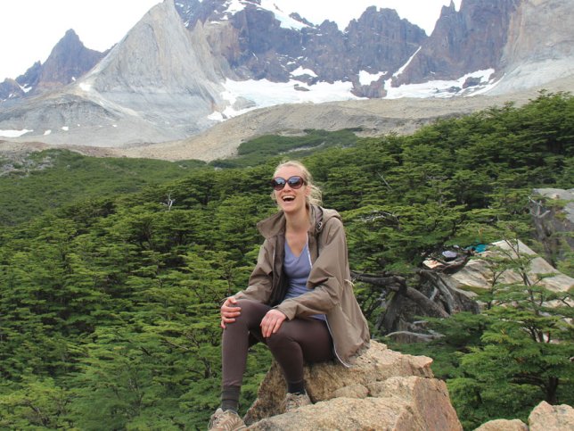 vrouw zit lachend op rots