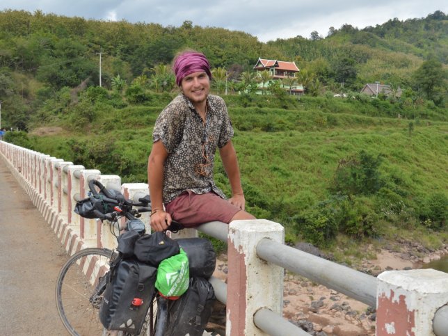 man zit op rand brug met fiets