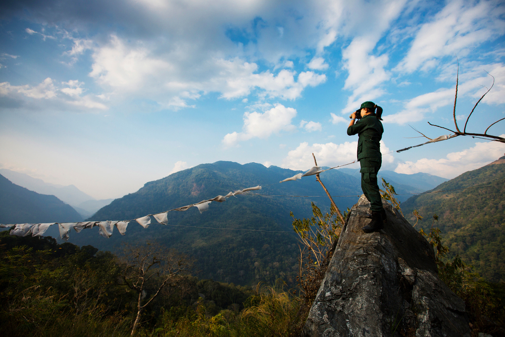 Vrouw kijkt in verrekijker boven op berg